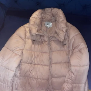 Rosa  pufferjacka från Isolde - Säljer en snygg rosa pufferjacka från Isolde. Jackan har en dragkedja framtill och en hög krage för extra värme. Perfekt för kyliga dagar. Det är inte beige det är rosa men det ser beige i bilden. Så färgen Rosa