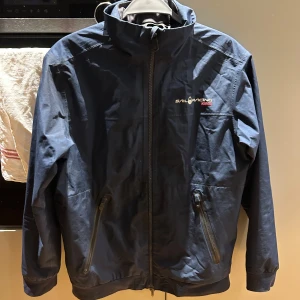 Blå jacka från Sail Racing - Snygg blå jacka från Sail Racing med GORE-TEX-material för extra skydd mot väder. Jackan har dragkedja framtill och två praktiska fickor med dragkedjor. Perfekt för utomhusaktiviteter. Skicka gärna prisförslag!!