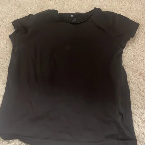 Svart t-shirt från H&M - En mörkgrå t-shirt från H&M i mjukt material. Perfekt basplagg för alla tillfällen. Kortärmad och rund halsringning.