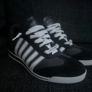 Dsquared2 Skor Fint skick - Snygga svarta sneakers från Dsquared2 med vita ränder och snörning. Tillverkade i Italien med en stilren design. Skorna är använda vid få tillfällen och är i mycket fint skick. Skorna behöver sulor då dem andra slängts pga egen anpassade.