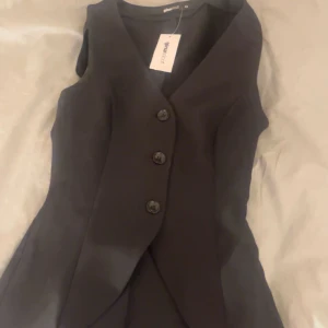 Svart väst från gina tricot - Elegant svart väst från gina tricot med tre knappar framtill. Perfekt för en stilren look. Aldrig använd och lappen är kvar. Säljer eftersom den är lite för liten❤️