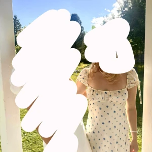 Vit klänning med blå blommor från Zara  - Säljer denna söta vita klänning med små blå blommor, perfekt till midsommar. Använd en gång