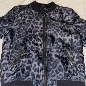 Leopardmönstrad bomberjacka från NEO NOIR - Snygg och unik leopardmönstrad bomberjacka från NEO NOIR i grå och svart. Jackan har dragkedja framtill och praktiska fickor med dragkedjor. 