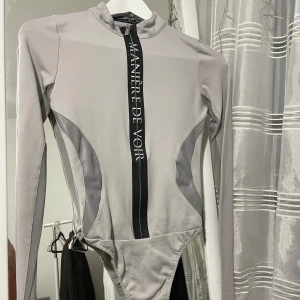 Grå body med meshdetaljer - Supersnygg cool body från Manière de Voir (franskt företag). Snatchar kroppen och man kan dra ner dragkedjan om man vill ha urringat 🩶 använd typ två ggr