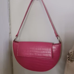 Rosa axelväska från Pull&Bear - Snygg rosa axelväska från Pull&Bear med krokodilpräglat mönster. Perfekt för att ge en färgklick till din outfit! Den är i fint skick och använd vid fåtal tillfällen🫶