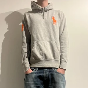 Ralph Lauren Hoddie - Snygg grå hoodie från Ralph Lauren med en stor orange logga på bröstet och en mindre på ärmen. 