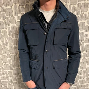  Massimo Dutti Field jacket - Snygg blå jacka från Massimo Dutti med flera fickor och knappar. Perfekt för en stilren look. Jackan har en klassisk design med en modern touch.