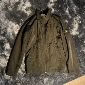 Svart jacka från Stone Island - Säljer en svart jacka från Stone Island i storlek M. Jackan har en dragkedja framtill och en klassisk design med långärmade ärmar. Tillverkad av 80% polyester och 20% bomull, vilket gör den både slitstark och bekväm.   Hör av er vid frågor// Liam