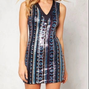 Glittrig klänning med paljetter - Snygg ärmlös klänning med ett glittrigt mönster i blått och rosa. Klänningen har en v-ringad design och är dekorerad med paljetter som ger en festlig look. Figurnära passform som ger en lyxig look på nyårsafton 