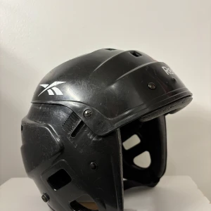 Hockey/skridskohjälm - Skridskohjälm i bra skick. Gör att ändra storlek med hjälp av skruvarna. Lite repig på utsidan mest av att ha legat i väskan. Fungerar bra som pulkahjälm/skridskohjälm/hockeyhjälm. Storlek 50-58 cm. 