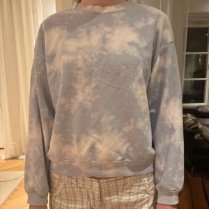 Blå och vit sweatshirt - Säljer en bekväm och stilren blå och vit sweatshirt med batikmönster. Tröjan har långa ärmar och en rund halsringning, perfekt för en avslappnad look.