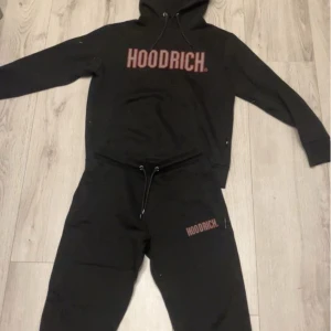 Svart Dress från Hoodrich - Snygg svart hoodie från Hoodrich med röd logga på bröstet. Perfekt för en avslappnad stil. Den har en klassisk huva med dragsko och långa ärmar. Ny pris: 1899 kr. Köpt från JD Sports. 