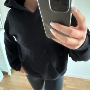 Svart hoodie - Säljer en klassisk svart hoodie med luva och ficka framtill. Perfekt för en avslappnad stil.