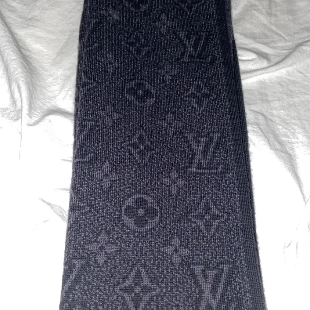 Elegant svart halsduk från Louis Vuitton med det ikoniska monogrammönstret. Perfekt för att hålla stilen under kyliga dagar. Den har en lyxig känsla och är ett måste för modeälskare. Den är oanvänd och ny. Skick 10/10. Asusteet.