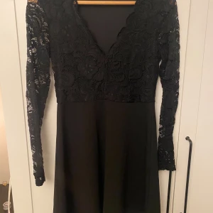 Svart spetsklänning från Bubbleroom - Elegant svart klänning från Bubbleroom med v-ringad spetsöverdel och långa spetsärmar. Kjoldelen är slät medan överdelen samt ärmarna är i spets. Perfekt till jul och nyårsfirandet💕💕