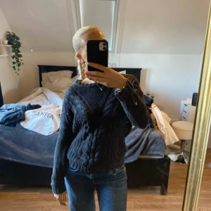 Mörkgrå stickad tröja - Säljer en mysig mörkgrå stickad tröja med kabelstickat mönster. Tröjan har långa ärmar och en rund halsringning, perfekt för kyligare dagar.