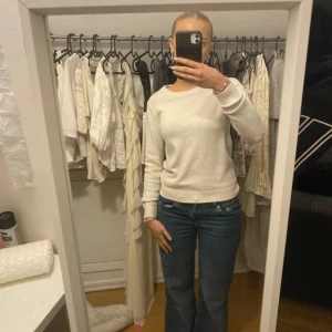 Vit stickad tröja - Säljer en stilren vit stickad tröja med rund hals och långa ärmar. Perfekt för en avslappnad look. Tröjan har ribbade muddar vid ärmslut och nederkant.
