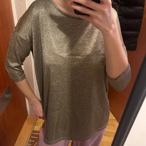 Beige T-shirt från H&M - Säljer en beige tröja från H&M med trekvartsärm. Perfekt för en avslappnad stil. Tröjan har en lös passform och är tillverkad i ett mjukt material.