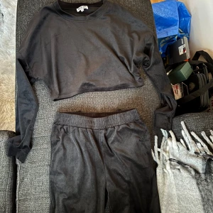Svart croppad tröja och byxor från Madlady - Säljer ett svart set från Madlady i storlek S. Tröjan är croppad med långa ärmar och byxorna har en elastisk midja för extra komfort. Perfekt för en avslappnad stil.