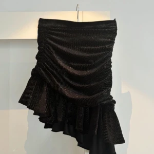 Svart glittrig kjol med volang - Trendig svart glittrig volangkjol som man även kan ha som topp! Perfekt nu till nyår🙌🏼 Säljer pga för liten för mig! Lappen är borta men den jag köpte av sa att den var från Zara!