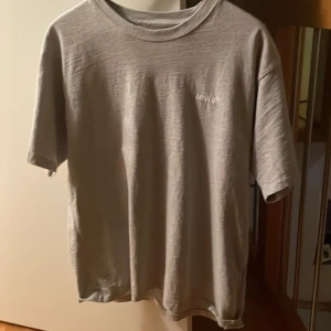 Grå t-shirt från Levi's - Säljer en stilren grå t-shirt från Levi's. Den har en klassisk passform med korta ärmar och rund hals. Perfekt för en avslappnad look. Aldrig använd då den inte passade i storlek