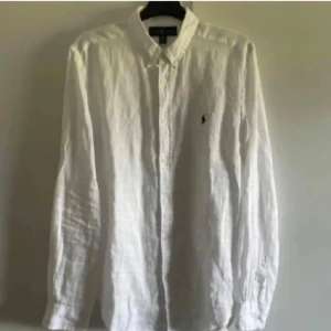 Vit linneskjorta från Ralph Lauren - Säljer en klassisk vit linneskjorta från Ralph Lauren med knappar och broderad logga på bröstet. Skjortan har en avslappnad passform och långa ärmar, perfekt för en stilren look. Storlek xl för barn så passar typ s eller xs. Inte använd mer än två gånger