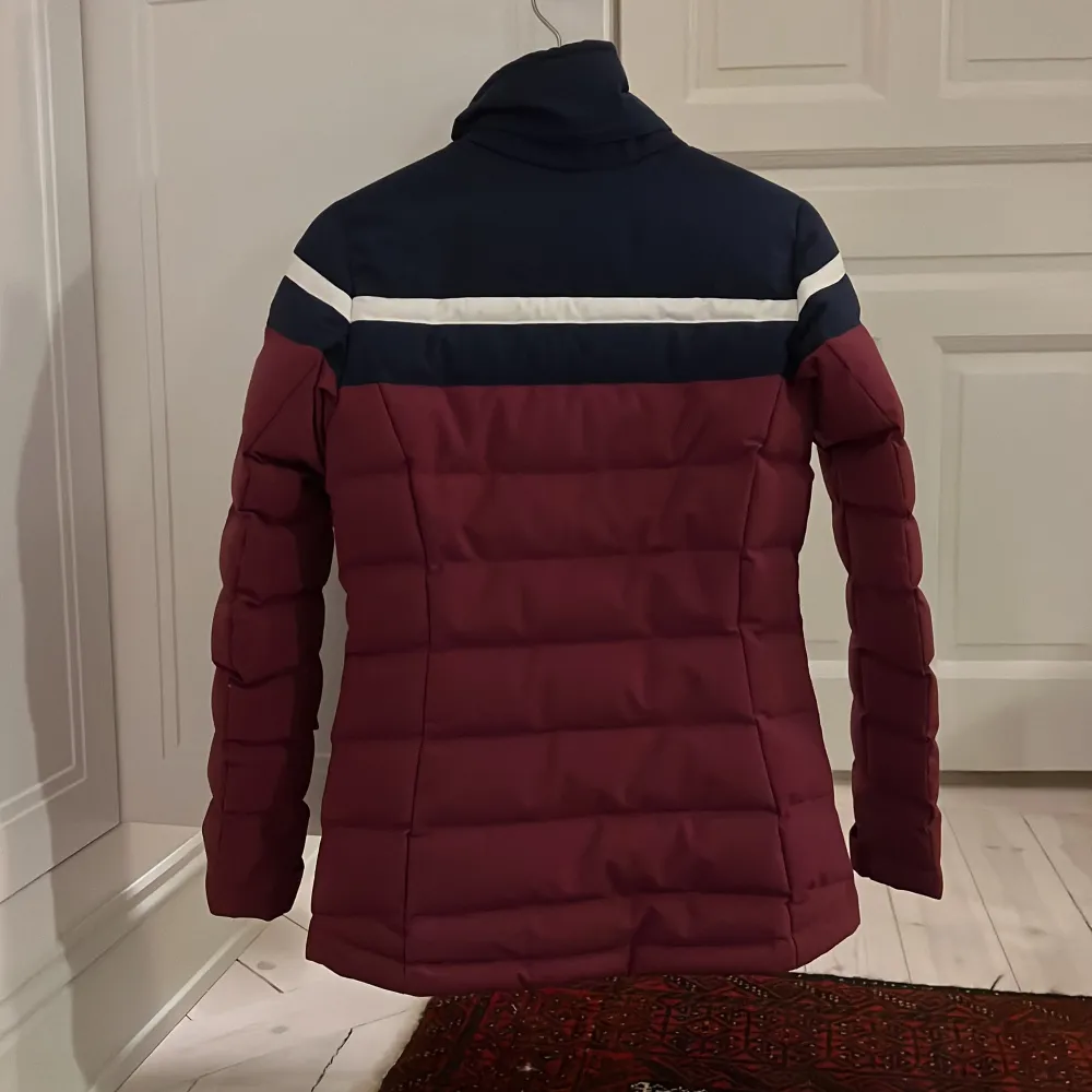 Skidjacka från J.Lindeberg med vita detaljer. Jackan har en dragkedja och knappar framtill samt långa ärmar. Köptes för 4600kr och säljer för 3000kr men priset kan diskuteras. Takit.