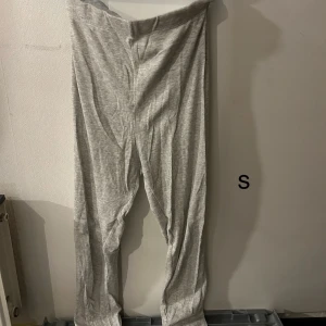 Grå mjukisbyxor - Bekväma grå mjukisbyxor i ribbat material. Perfekta för en avslappnad dag hemma eller en lugn promenad. Byxorna har en loose passform och är tillverkade i ett mjukt och stretchigt tyg.