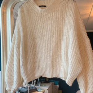 Vit stickad tröja från Gina Tricot - Mysig vit stickad tröja från Gina Tricot med en luftig design. Tröjan har långa balkong ärmar och en rund halsringning, Den har en lös passform och ribbade kanter. Som ny 