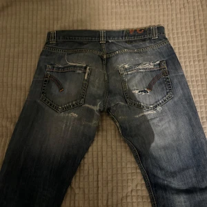 Vintage jeans  - Säljer ett par blå jeans med coola slitningar och en klassisk femficksdesign. De har en knappgylf och är i en straight passform. Midjemått: 34 innreben: 95. Kan gå ner i pris!
