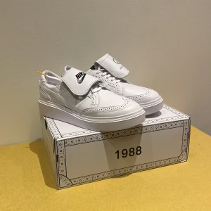 Vita Nike KWOND01 x PEACEMINUSONE - Snygga vita Nike KWOND01 i samarbete med PEACEMINUSONE. Skorna har en unik design med broguedetaljer och logotyper. Perfekta för dig som vill ha något annorlunda och stilrent. Aldrig använda, lådan ingår vid köp. 
