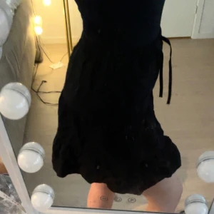 Svart kjol med knytband - Snygg svart kjol med knytband i midjan. Perfekt för en stilren look. Kjolen har en lätt utställd form och är gjord i ett bekvämt material.