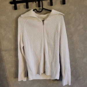 Vit ribbad tröja från Esprit - Säljer en stilren vit ribbad tröja från Esprit med dragkedja framtill. Tröjan har långa ärmar och en hög krage som kan vikas ner. Perfekt för kyligare dagar.