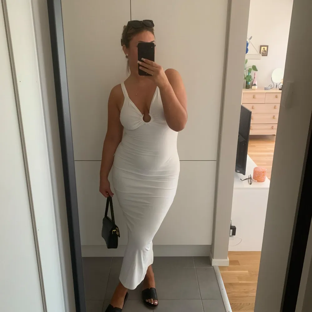 Elegant vit långklänning med unika cut-out detaljer framtill och baktill. Aldrig använt den!. Mekot.