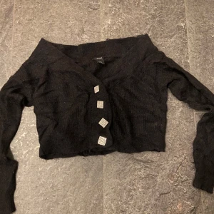 Svart croppad kofta med knappar - Snygg svart croppad kofta med unika fyrkantiga knappar. Perfekt för en trendig look. Passar bra till både jeans och kjol.