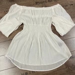 Vit offshoulder kläning från Sara Kelly, by Ellos - Säljer en stilren vit offshoulder kläning från Sara Kelly, by Ellos. Klänningen har elastiska muddar och en smickrande passform. Perfekt för en somrig look eller till studenten!