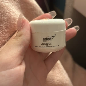 Akrylpulver från Nded - Litet vitt burk med akrylpulver från Nded, perfekt för nagelförlängning och design. Burken har varningssymboler och en hållbarhet på 12 månader efter öppning. Färgen är en rosa glittrig nästan helt full..