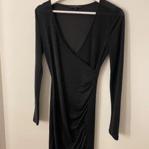 Svart omlottklänning från Vero Moda - Säljer denna klänning från veromoda som är glittrig då jag endast använt den en gång, passar perfekt till nyårsafton🥰