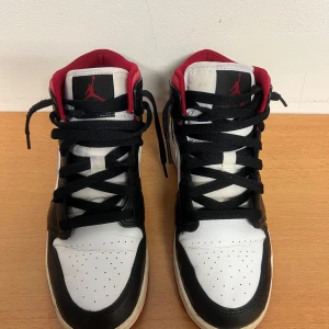 Nike Air Jordans i svart, vitt och rött - Snygga Nike Air Jordans i klassisk färgkombination av svart, vitt och rött. Skorna kommer i mid-modellen med snörning och den ikoniska Nike-loggan på sidan. Dom är i bra skick men tecken på användning finns🤍