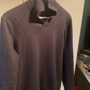 Mörkblå tröja från Massimo Dutti - Säljer en stilren mörkblå tröja från Massimo Dutti. Tröjan har en hög krage och är tillverkad i ull, vilket gör den perfekt för kyligare dagar. Den har långa ärmar och en enkel design som passar till många olika stilar.