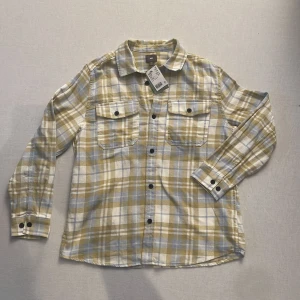 Helt ny Rutig skjorta från H&M - Snygg rutig skjorta från H&M. Skjortan har långa ärmar och två bröstfickor med knappar. Perfekt för en avslappnad stil. Inköpt för 249 men säljer för endast 100kr då den inte kommit till användning 