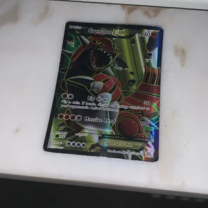 Groudon EX Pokémonkort - Säljer ett Groudon EX Pokémonkort med holografisk design. Kortet har 180 HP och attacker som Rip Claw och Massive Rend. Perfekt för samlare eller spelare som vill förstärka sin kortlek.