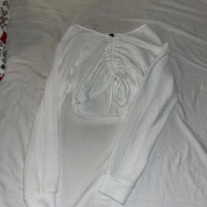 Vit stickad tröja från Shein - Säljer en vit stickad tröja från Shein med snörning framtill. Tröjan har långa ärmar och en croppad passform.