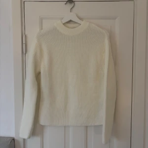 Vit stickad tröja från NA-KD - Säljer en stilren vit stickad tröja från NA-KD. Tröjan har en klassisk rund hals och långa ärmar, perfekt för kyligare dagar. Den är i storlek XXS och passar utmärkt för lager-på-lager-stil.
