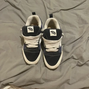 Svart/blå/vit vans knu  - Snygga Vans sneakers i svart och vitt med klassisk design. Skorna har snörning och en bekväm passform. Perfekta för en avslappnad stil.