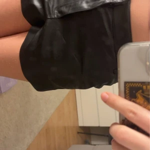 Svarta shorts från Zara - Snygga svarta shorts i skinnimitation från Zara. Perfekta för en stilren look med mid waist och en bekväm passform. Passar utmärkt till både vardag och fest.
