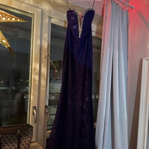 Mörkblå långklänning med paljetter - Elegant mörkblå långklänning med vacker spets och glittrande paljetter längs den hjärtformade urringningen. En paljett sitter löst men går enkelt att fixa!