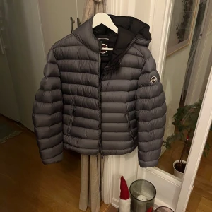 Grå vinterjacka från Colmar - Snygg grå vinterjacka från Colmar med huva och dragkedja. Perfekt för kyliga dagar. Jackan har en stilren design med Colmar-logga på ärmen. Perfekt skick!