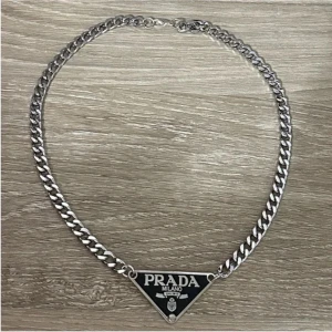 Halsband från Prada - Snyggt silverfärgat halsband från Prada. Köpt på en second hand butik i Bordeaux, Frankrike. Kan ej garantera äktheten. Perfekt för att ge en stilren touch till din outfit.