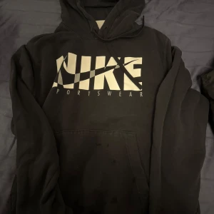 Svart hoodie från Nike - Säljer en svart hoodie från Nike med stor logga i vitt på framsidan. Den har en klassisk design med huva och känguruficka. Perfekt för en avslappnad stil.